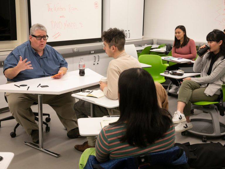 Students talking to a professor in a classroom